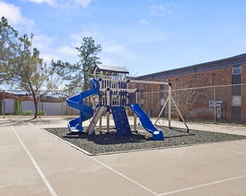 A blue and white playground slide in a parking lot.